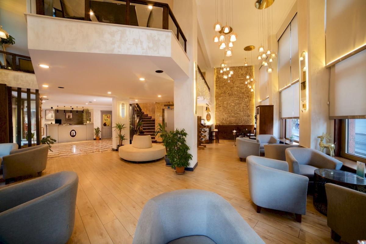 Lobby des Barin Hotels mit Holzboden, modernen Möbeln und Pflanzen.