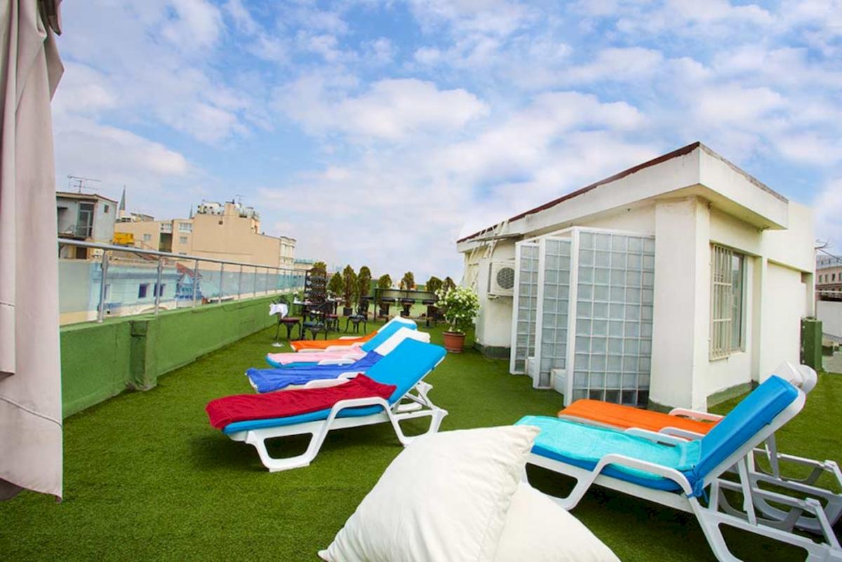 Dachterrasse des Barin Hotels mit mehreren Liegen und Kissen auf künstlichem Gras.