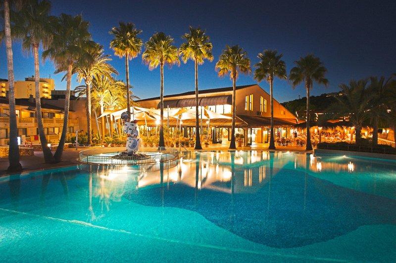 Pool des Royal Son Bou Family Clubs bei Nacht mit beleuchteten Gebäuden und Palmen.