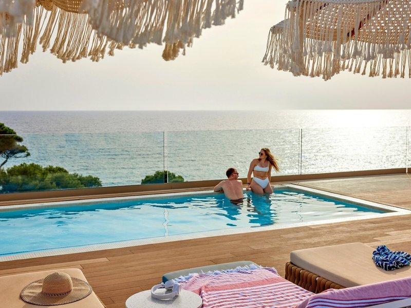 Paar im Swimmingpool des Victoria Menorca mit Blick auf das Meer