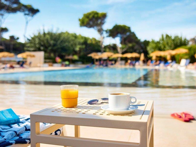 Kaffeetisch mit Pool im Hintergrund im Victoria Menorca Hotel