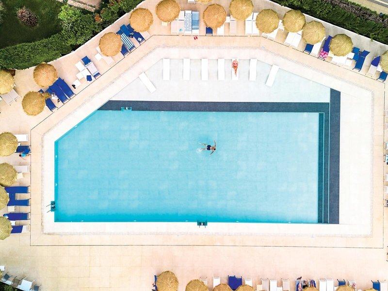 Oberirdischer Pool im Victoria Menorca Hotel mit Sonnenliegen und Sonnenschirmen.
