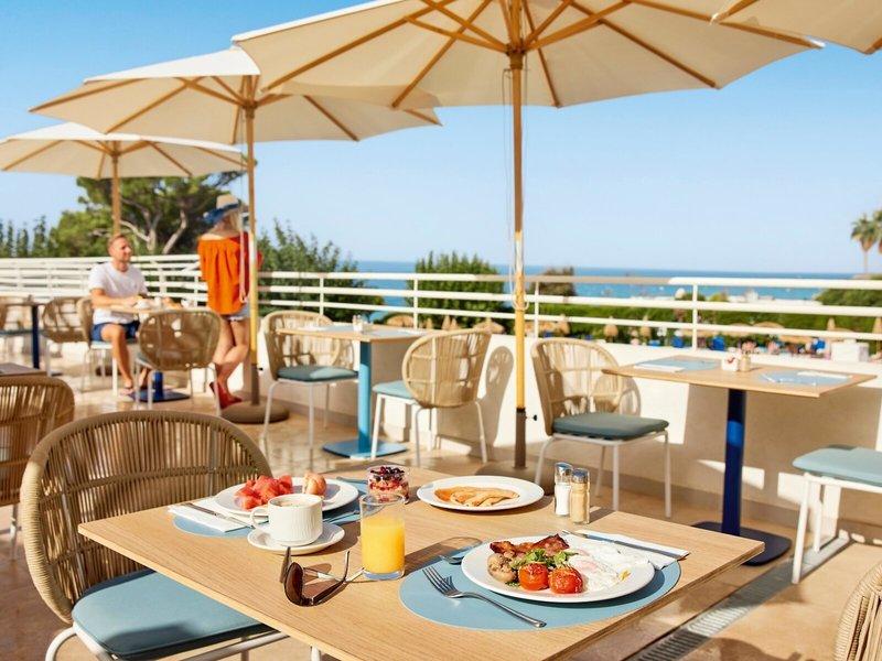 Frühstückstisch auf der Terrasse des Victoria Menorca Hotels mit Blick auf das Meer.