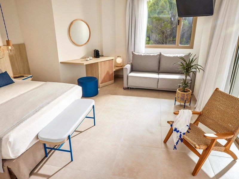 Victoria Menorca Hotelzimmer mit Doppelbett, Couch, Tisch und Fenster.