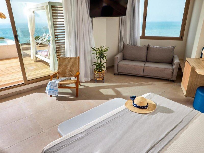Victoria Menorca Hotelzimmer mit Meerblick, Bett, Sofa und Fernseher.