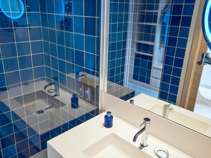 Badezimmer mit blauen Fliesen und einem Spiegel im Hotel Victoria Menorca.