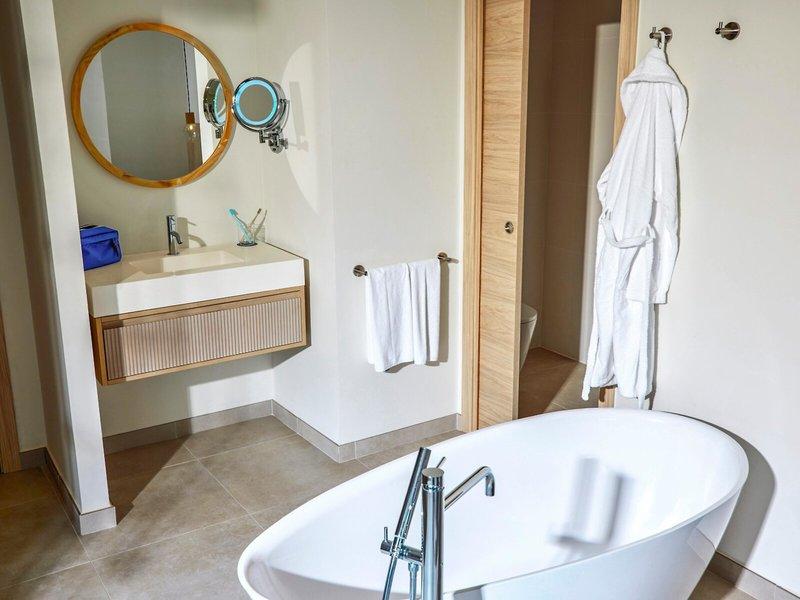 Badezimmer im Victoria Menorca Hotel mit Badewanne, Waschbecken und Spiegeln.