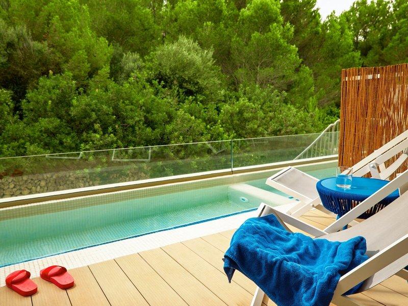 Poolterrasse im Victoria Menorca Hotel mit Blick auf umliegende Bäume.