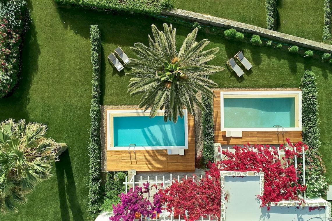 Luftaufnahme des Yria Island Boutique Hotels mit Swimmingpools und Liegestühlen.