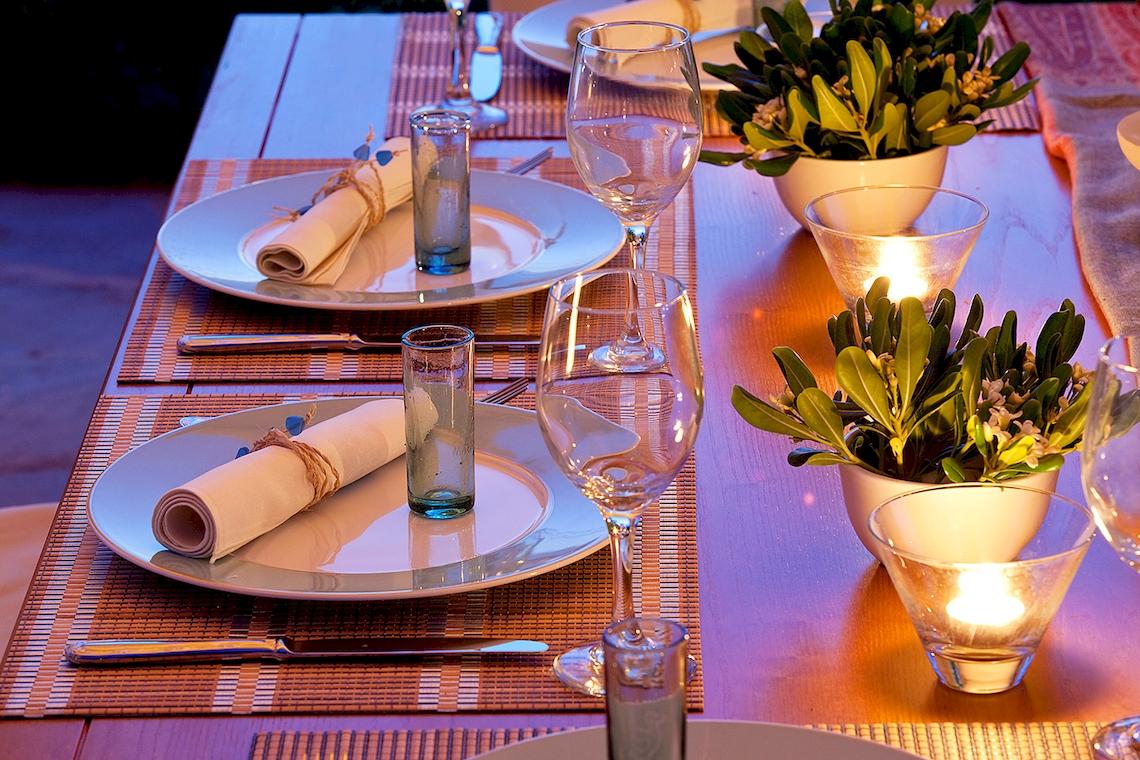 Gedeckter Esstisch im Yria Island Boutique Hotel & Spa mit Tellern, Gläsern und Kerzen.