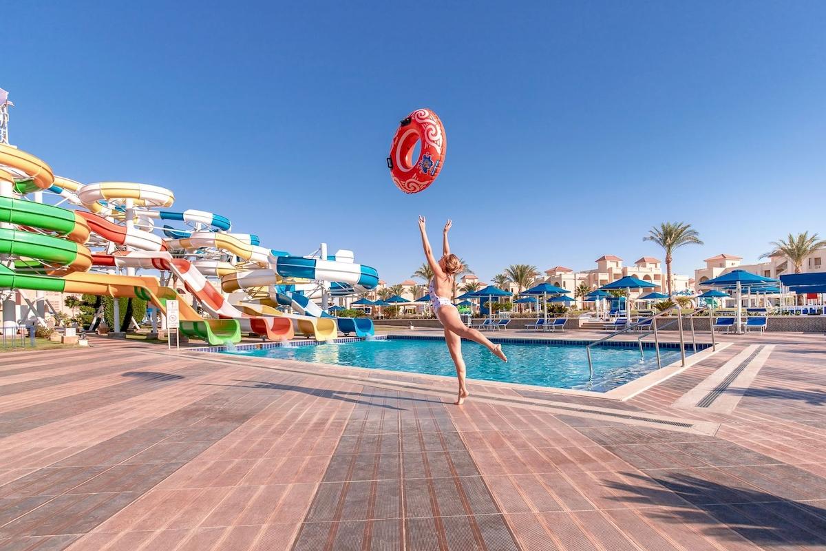 Frau springt mit Schwimmring vor Wasserrutschen im Pickalbatros Aqua Park Resort in Hurghada