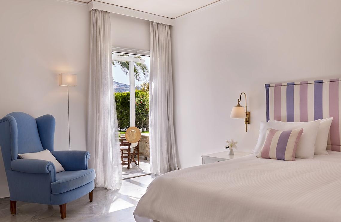 Schlafzimmer mit Bett, Stuhl und offenem Balkon im Yria Island Boutique Hotel & Spa.