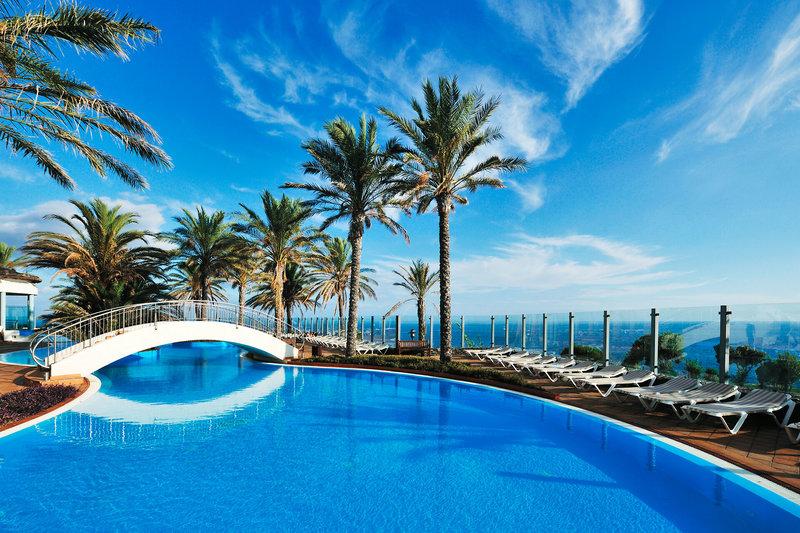 Außenpool des Pestana Grand Premium Ocean Resort mit Brücke und Liegestühlen.