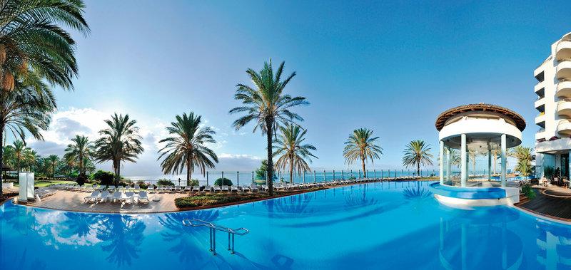Außenpool mit Loungestühlen und Palmen am Pestana Grand Premium Ocean Resort