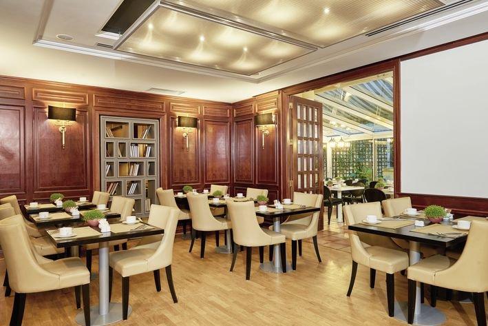 Innenansicht des Restaurants im Villa Marquis Melia Collection Hotel mit holzgetäfelten Wänden und runden Tischen.