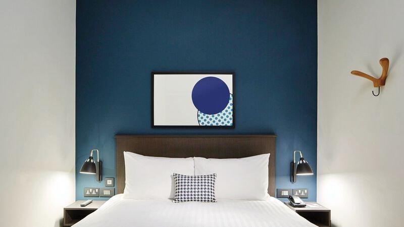 Hotelzimmer im Residence Inn by Marriott London Bridge mit blauer Wand, Bett und Dekoration.
