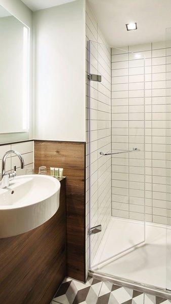 Badezimmer im Residence Inn by Marriott London Bridge mit einer Glasdusche, einem Waschbecken und Holzverkleidung.