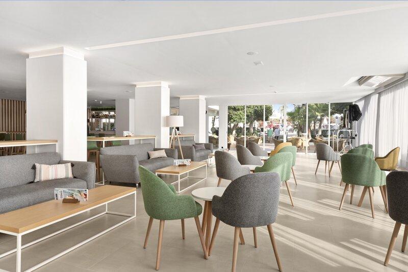 Lobbybereich des THB Gran Playa Hotels mit grauen Sofas und bunten Stühlen.