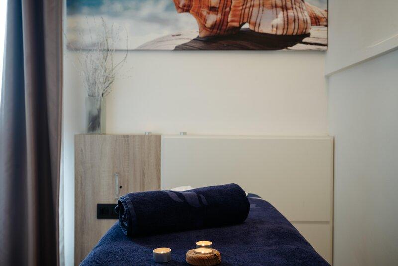 Massage-Raum im THB Gran Playa Hotel mit blauer Bettdecke, Kerzen und Kunstwerk an der Wand.