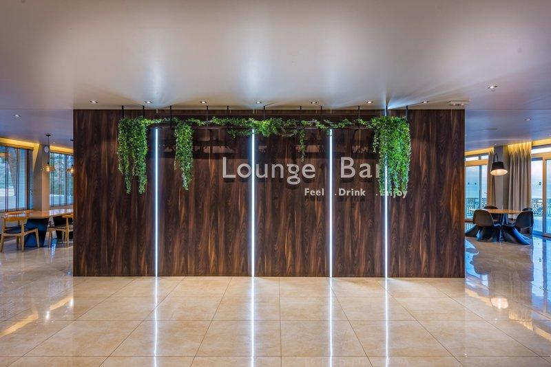 Innenansicht der Lounge Bar im Alexandra Beach Resort mit begrünter Wand und hellem Boden.