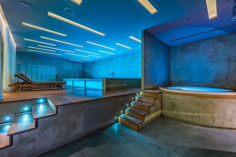 Innenbereich des Badezimmers im Alexandra Beach Resort mit beleuchteten Stufen und Whirlpool.