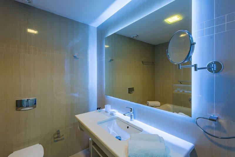 Badezimmer im Alexandra Beach Resort mit Spiegel, Waschbecken und Badewanne.