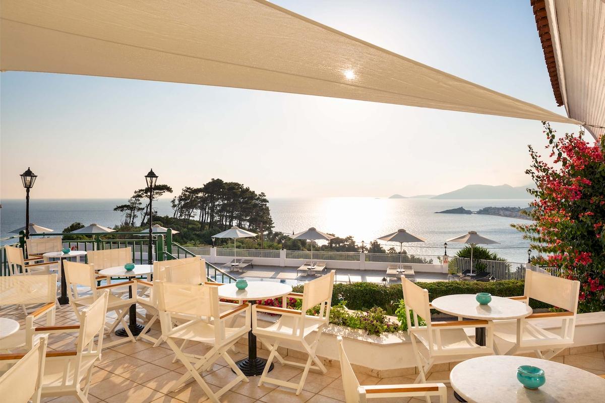 Außenterrasse des Kalidon Panorama Hotels mit Blick auf das Meer und grüne Bäume.