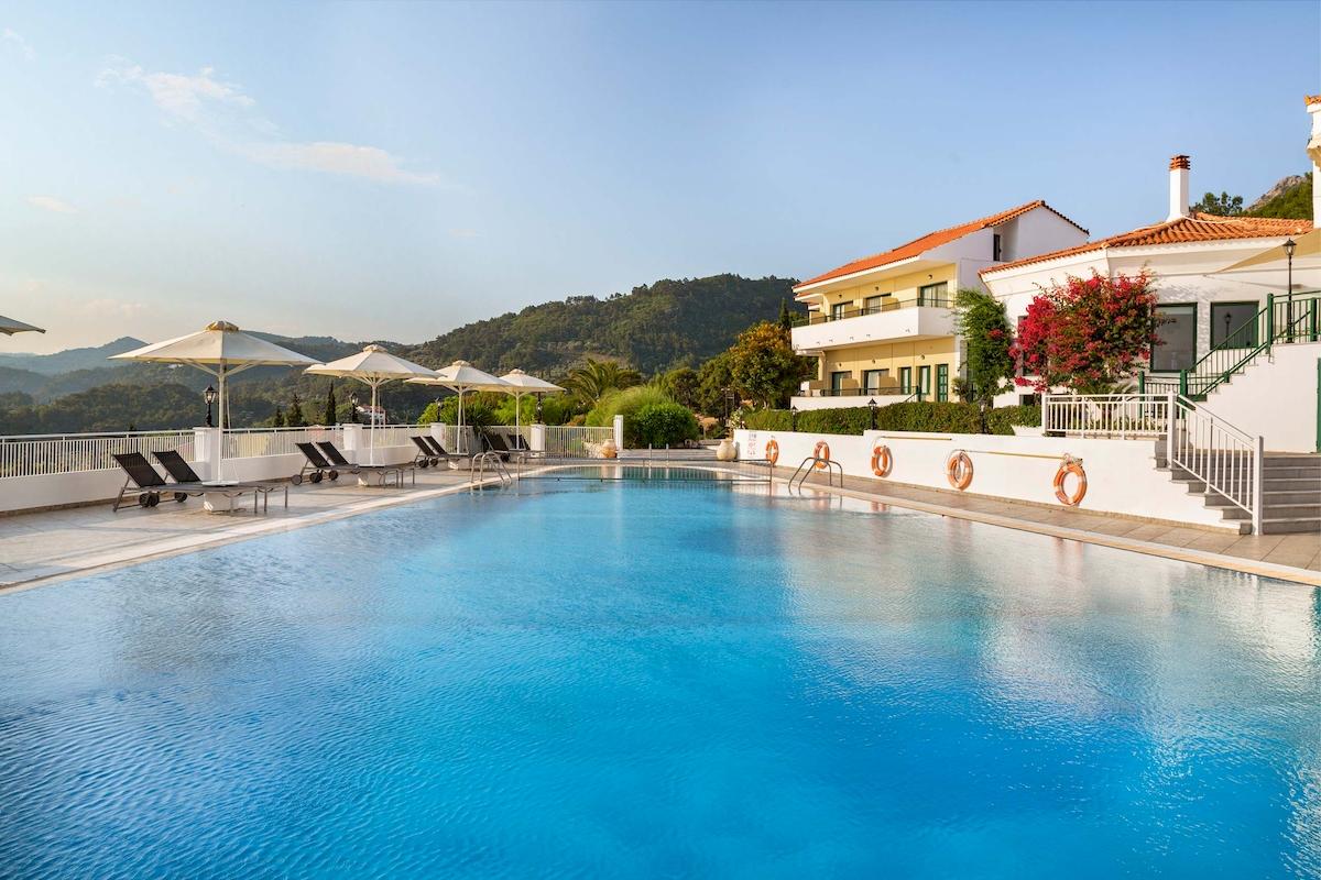 Außenpool am Kalidon Panorama Hotel mit Sonnenliegen und Bergen im Hintergrund