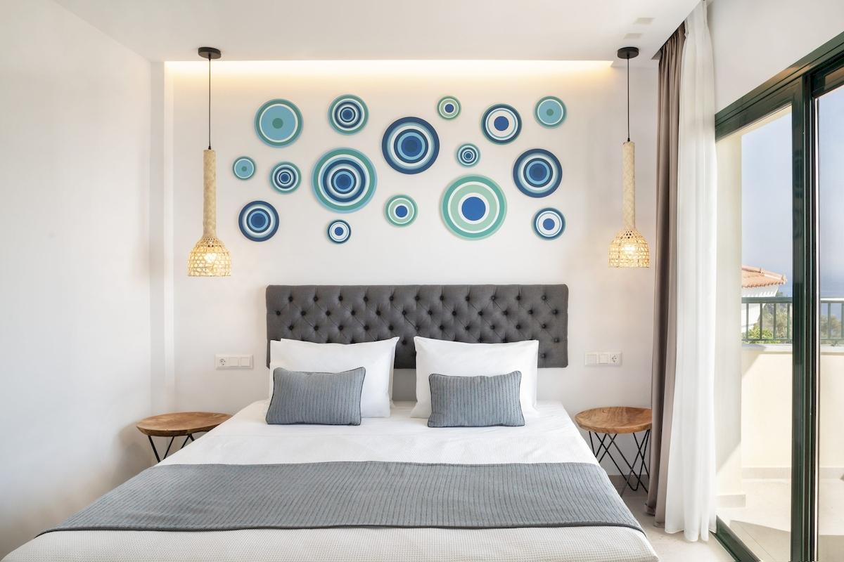 Schlafzimmer mit Bett, grauem Kopfteil und dekorativen blauen und grünen Kreisen an der Wand.