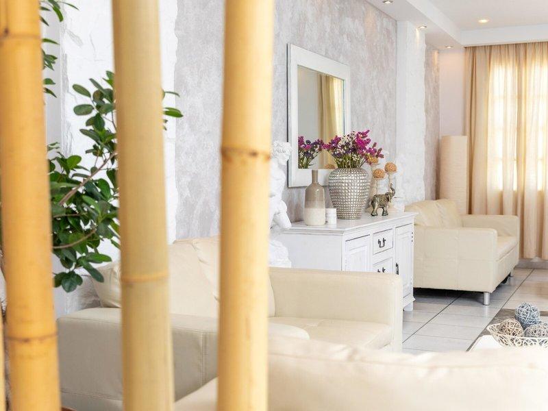 Wohnbereich des Golden Coast Hotels mit weißen Möbeln, einem Spiegel und einer Pflanze.