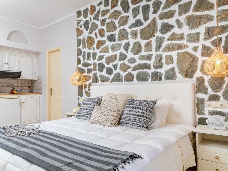 Schlafzimmer mit Steinwand und Bett, Kissen, Decken und Nachttisch