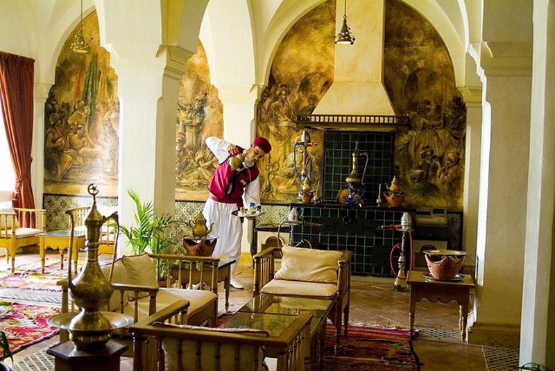 Ein traditioneller Kellner serviert Getränke in einem luxuriösen Hotelsalon.