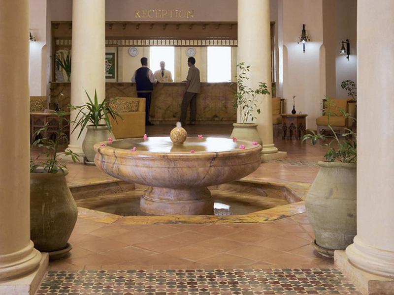 Empfangsbereich des Medina Belisaire & Thalasso Hotels mit einer Brunnenanlage und hohen Säulen.