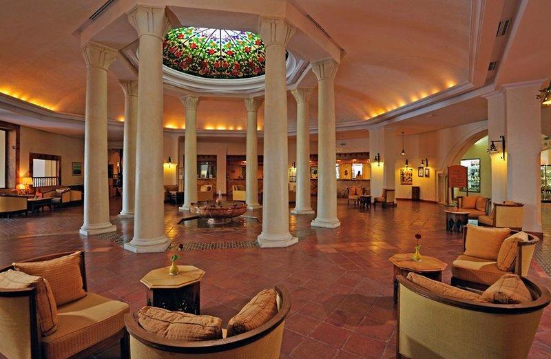 Innenansicht des Empfangsbereichs des Medina Belisaire & Thalasso Hotels mit Säulen und farbigem Glasdach