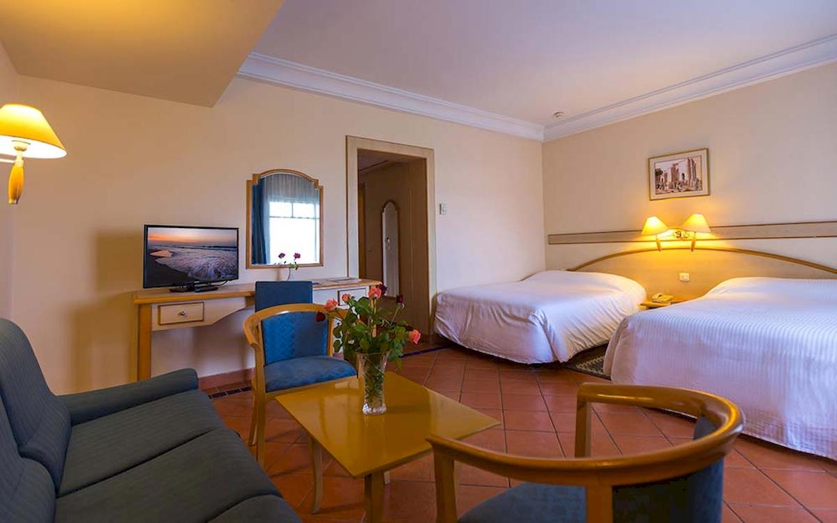 Zimmer im Medina Belisaire & Thalasso Hotel mit zwei Betten, Fernseher, Tisch und Sofa.