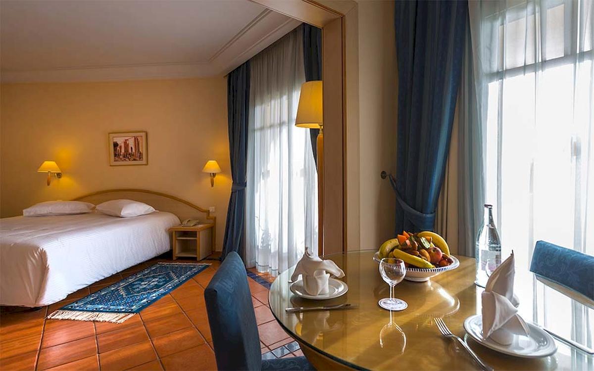 Innenansicht eines Hotelzimmers im Medina Belisaire mit Bett, Tisch und Fenstern.