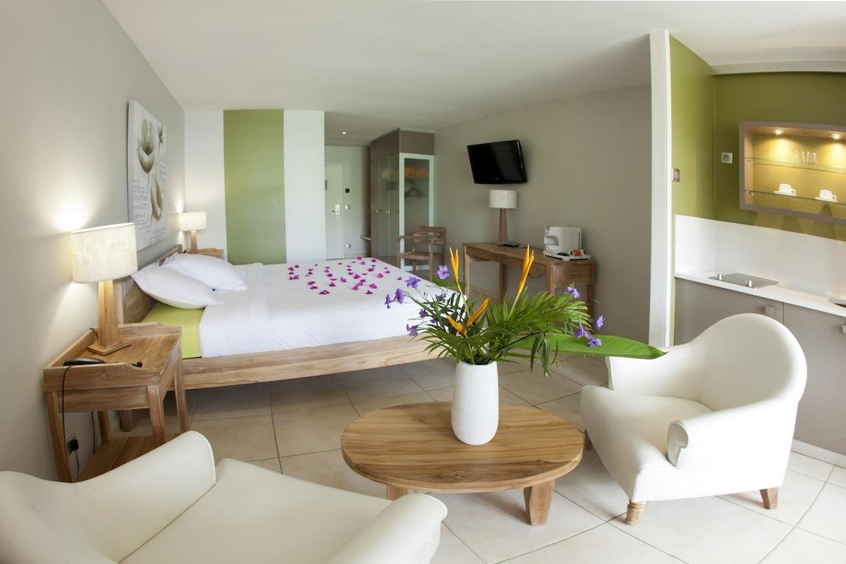 Schlafzimmer im La Pagerie - Tropical Garden Hotel mit Blumen auf dem Bett und weißem Interieur.