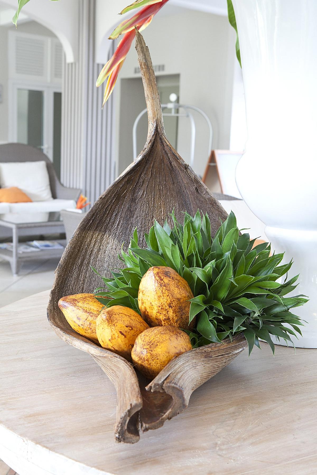 Ein Zimmer im La Pagerie - Tropical Garden Hotel mit einer großen Holzschale, die Früchte und Pflanzen enthält.