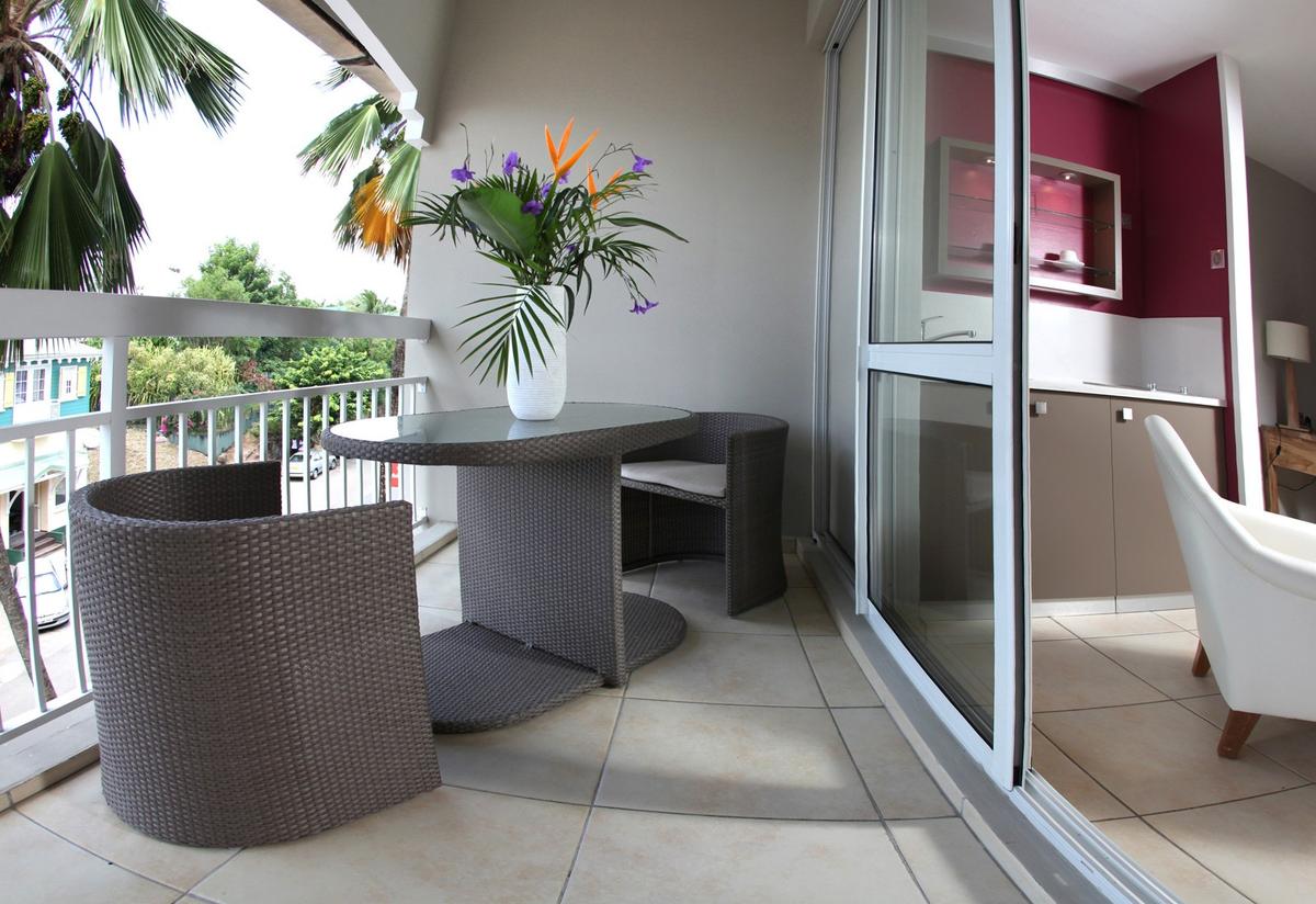 Ein Balkon des La Pagerie - Tropical Garden Hotel mit Tisch, Stühlen und einer Vase mit Blumen.