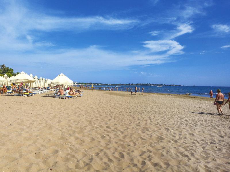 Foto des Strandes im Melas Holiday Village mit vielen Sonnenschirmen und Strandliegen