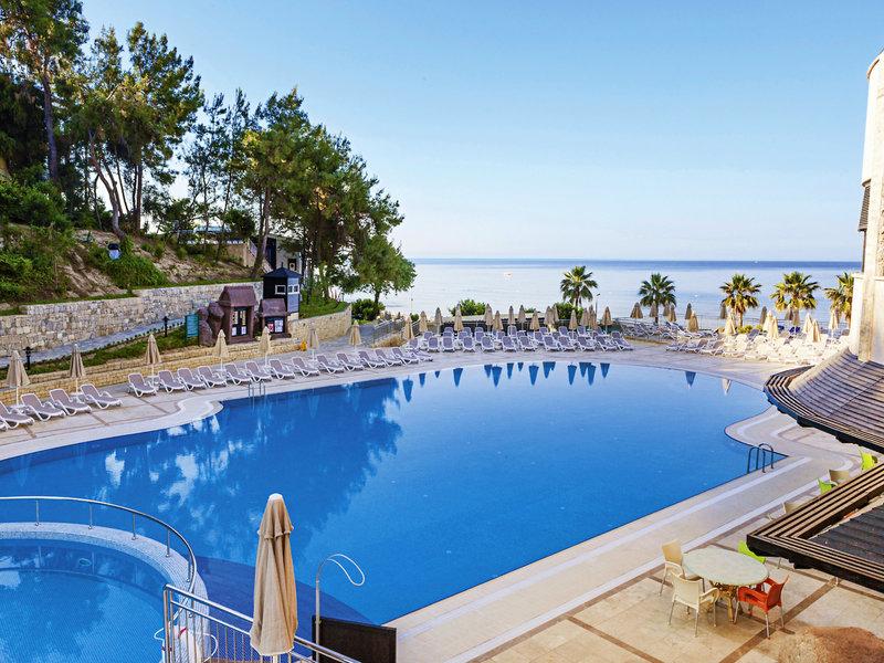 Außenpool des Melas Holiday Village mit Blick auf das Meer und Sonnenliegen