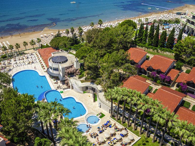 Luftaufnahme des Melas Holiday Village mit Pools, Gebäuden und einer Küste im Hintergrund