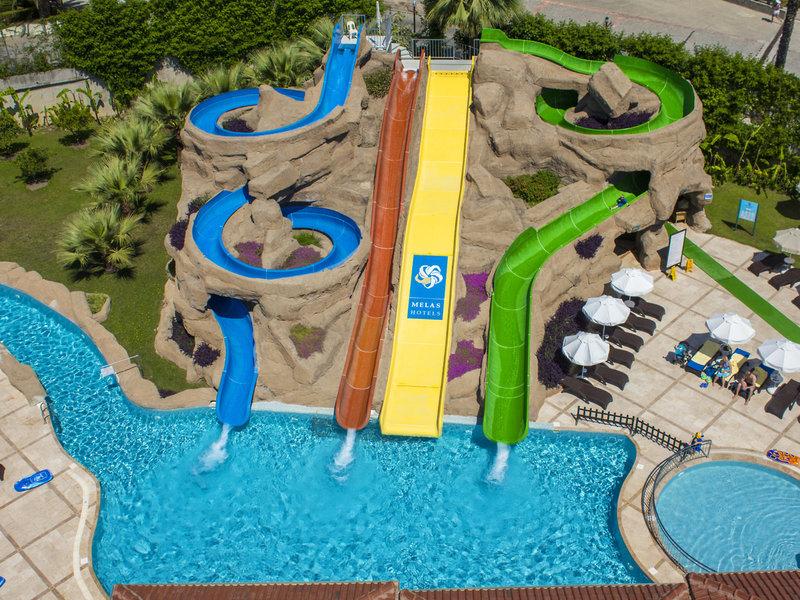 Luftaufnahme des Wasserrutschenbereichs im Melas Holiday Village mit drei Rutschen und Pools.