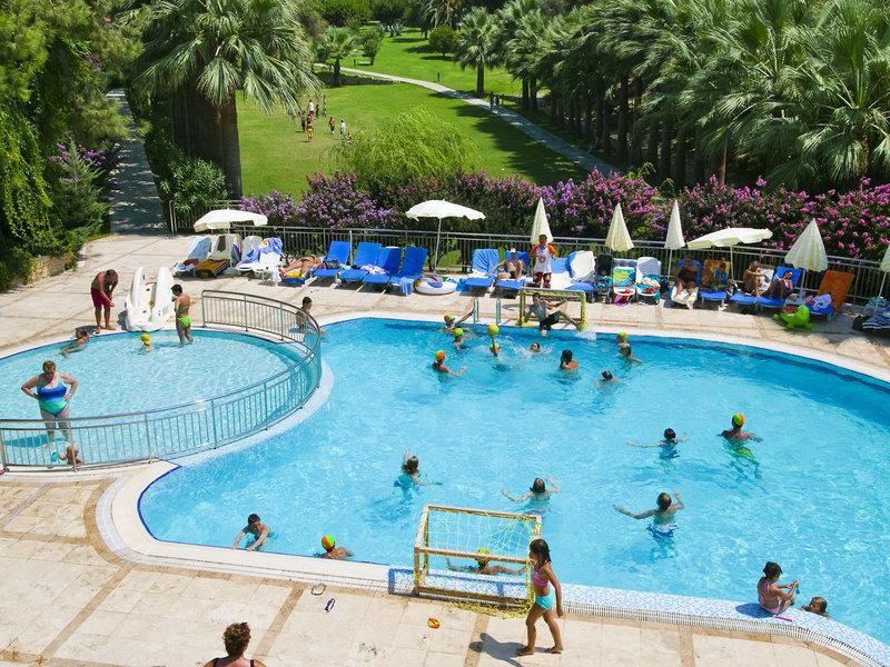 Mehrere Schwimmbecken im Melas Holiday Village mit vielen Kindern, die spielen und einige Erwachsene, die sich entspannen.