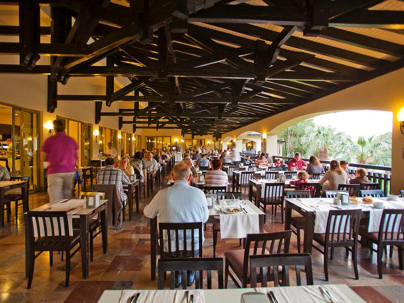 Innenansicht des Restaurants im Melas Holiday Village mit vielen Gästen an Tischen.