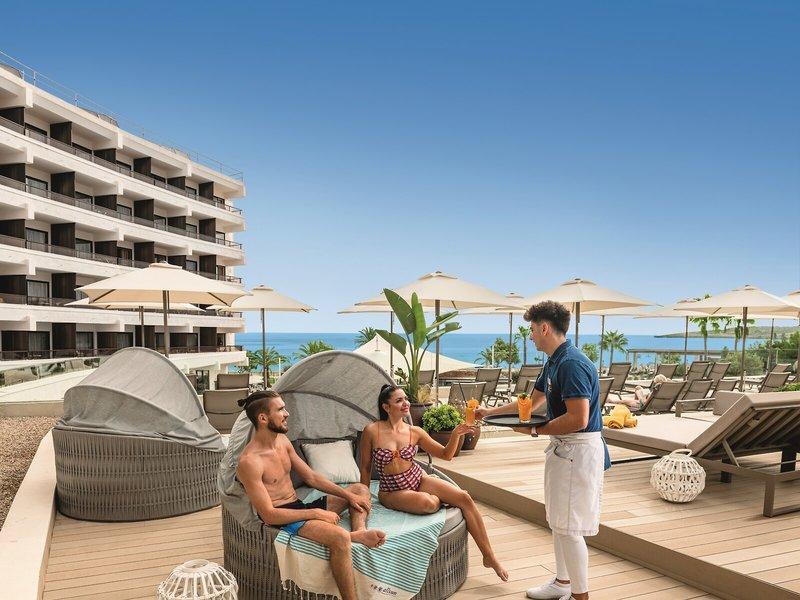 Hotelterrasse des Allsun Hotel Sumba mit Blick auf das Meer und Loungebereich mit Gästen