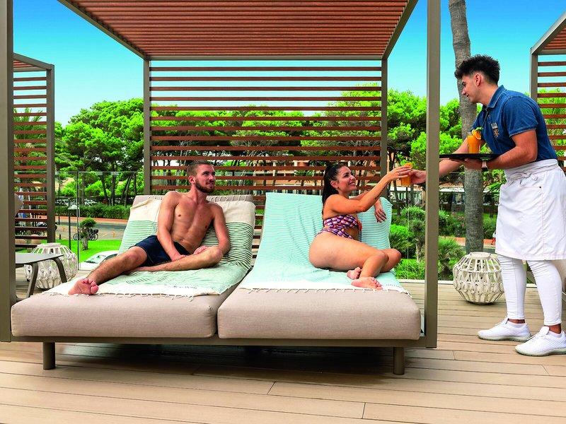 Gäste auf der Terrasse des Allsun Hotel Sumba, ein Kellner serviert Getränke.