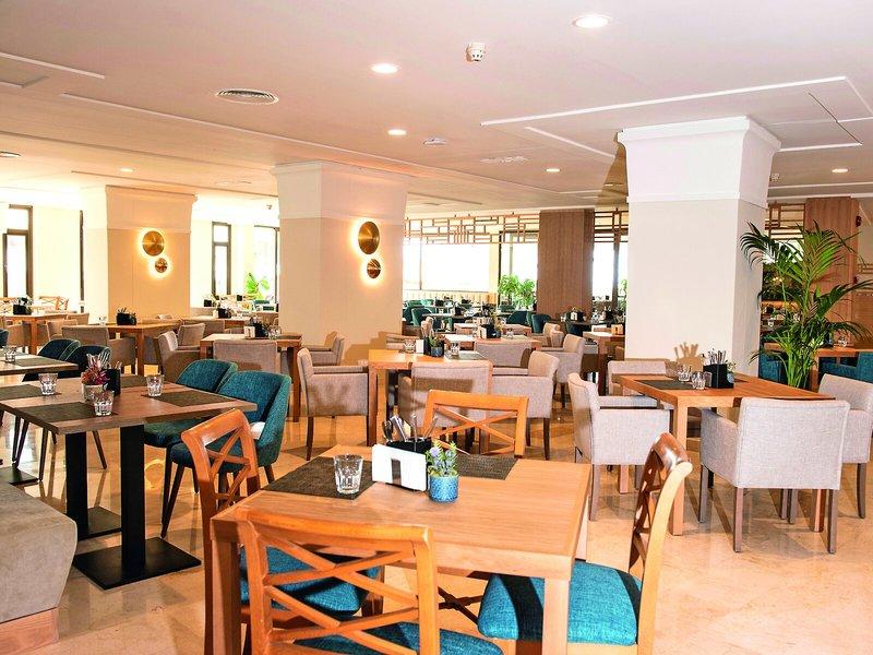 Innenansicht des Restaurants im Allsun Hotel Sumba mit runden Tischen und Stühlen.