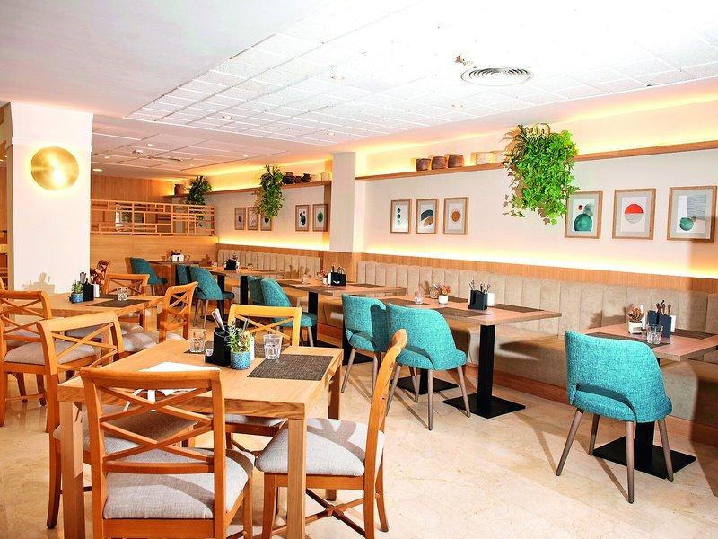 Innenansicht des Allsun Hotel Sumba Restaurant mit blauen Stühlen und Holztischen.