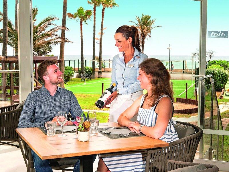 Eine Mitarbeiterin des Allsun Hotel Sumba serviert ein Paar am Tisch im Restaurant.